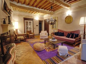 Ein gemütliches Wohnzimmer mit Kamin, einer Couch, einem Couchtisch und einem gemusterten Teppich.