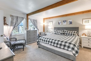 Een slaapkamer met een bed met ruitjesdeken, een dressoir, een stoel en een nachtkastje.