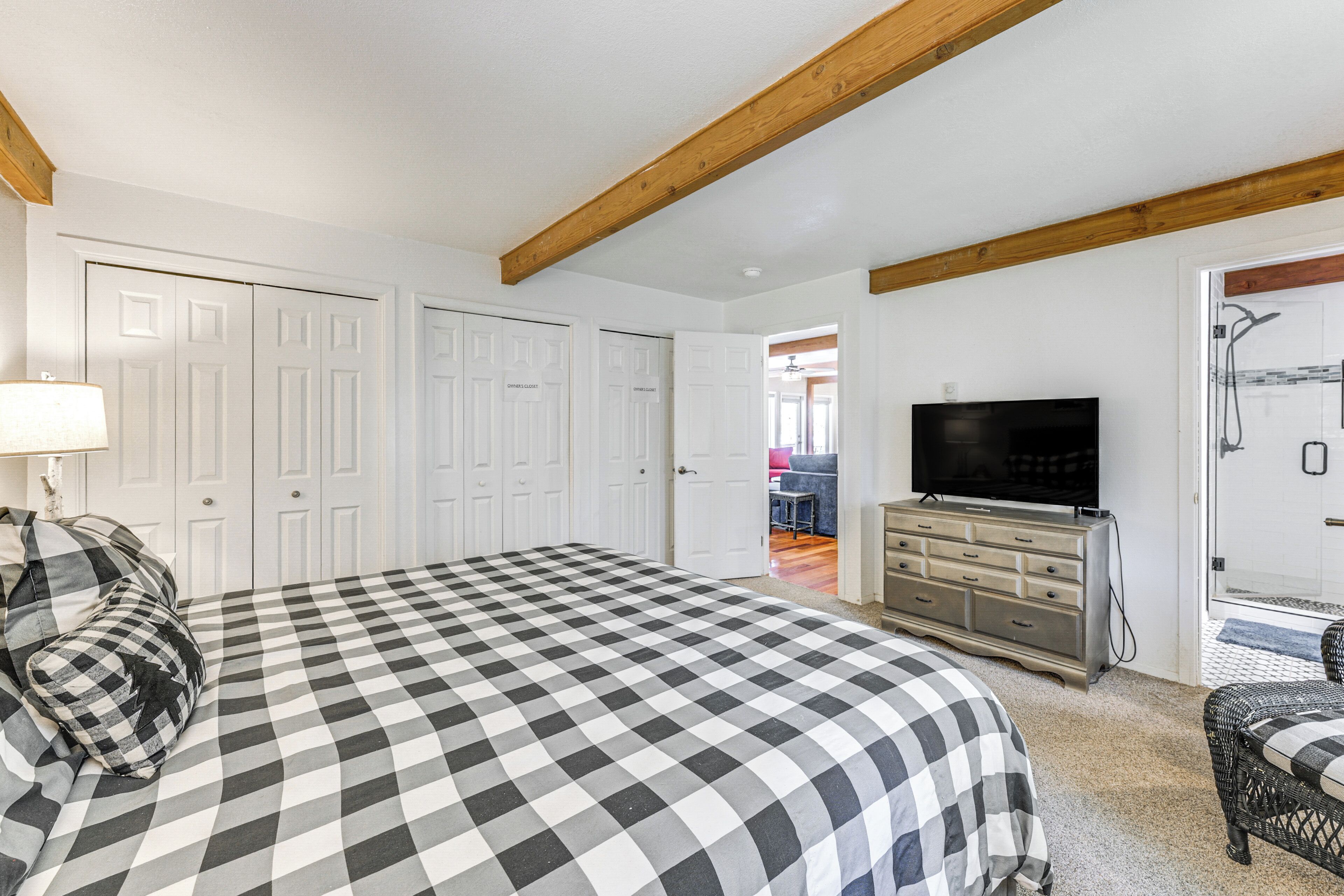 Une chambre à coucher avec une couvre-lit à carreaux, un téléviseur, une commode et une porte donnant sur une salle de bain.