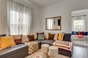Ein Wohnzimmer mit einer Eckcouch, einem Couchtisch, einem Teppich und einem großen Spiegel an der Wand.