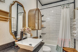 Ein Badezimmer mit einem weißen Waschbecken, einem Spiegel, einer Badewanne und einer Duschvorhang.