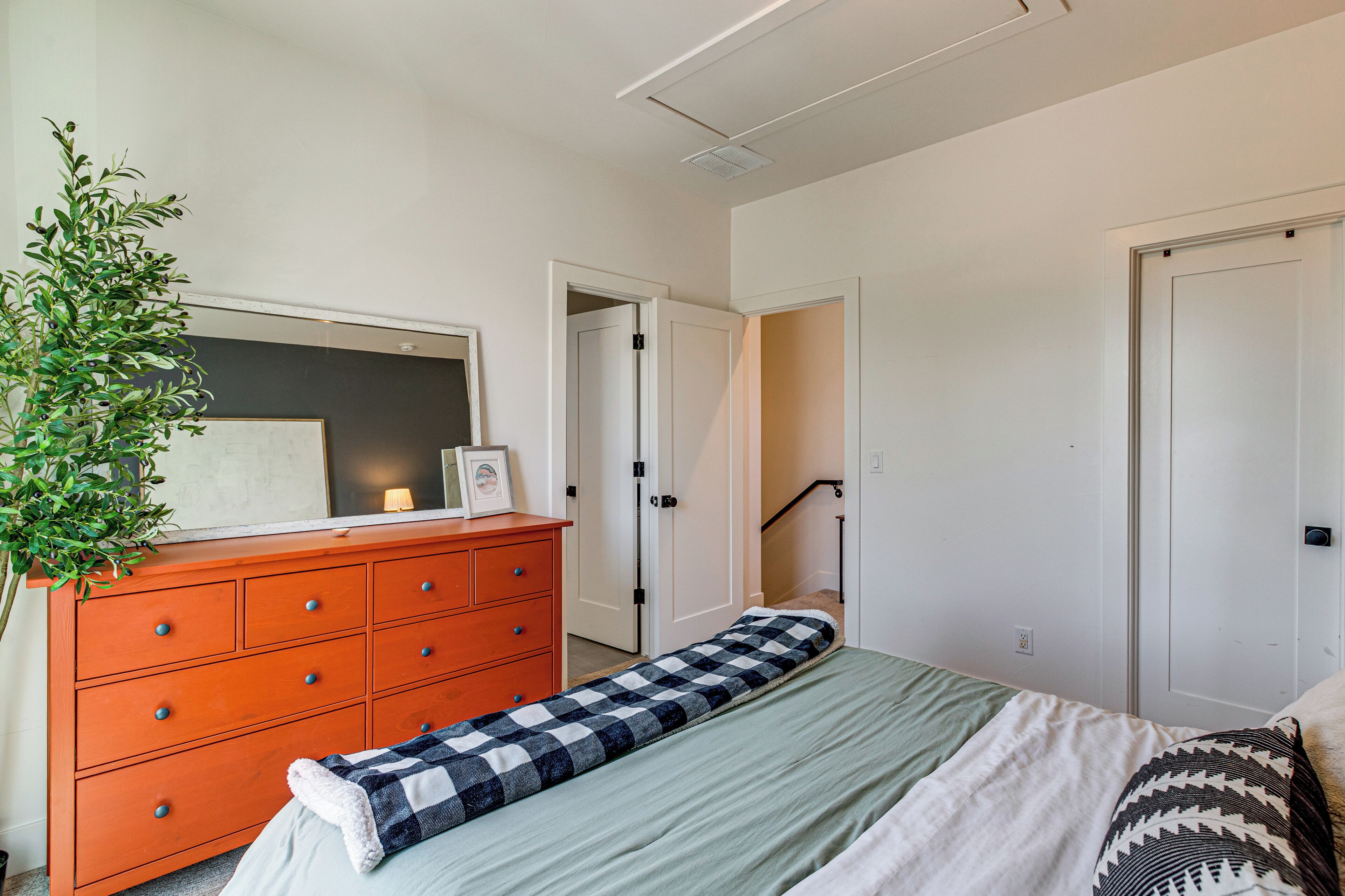 Ein Schlafzimmer mit Bett, Kommode und einer Topfpflanze.