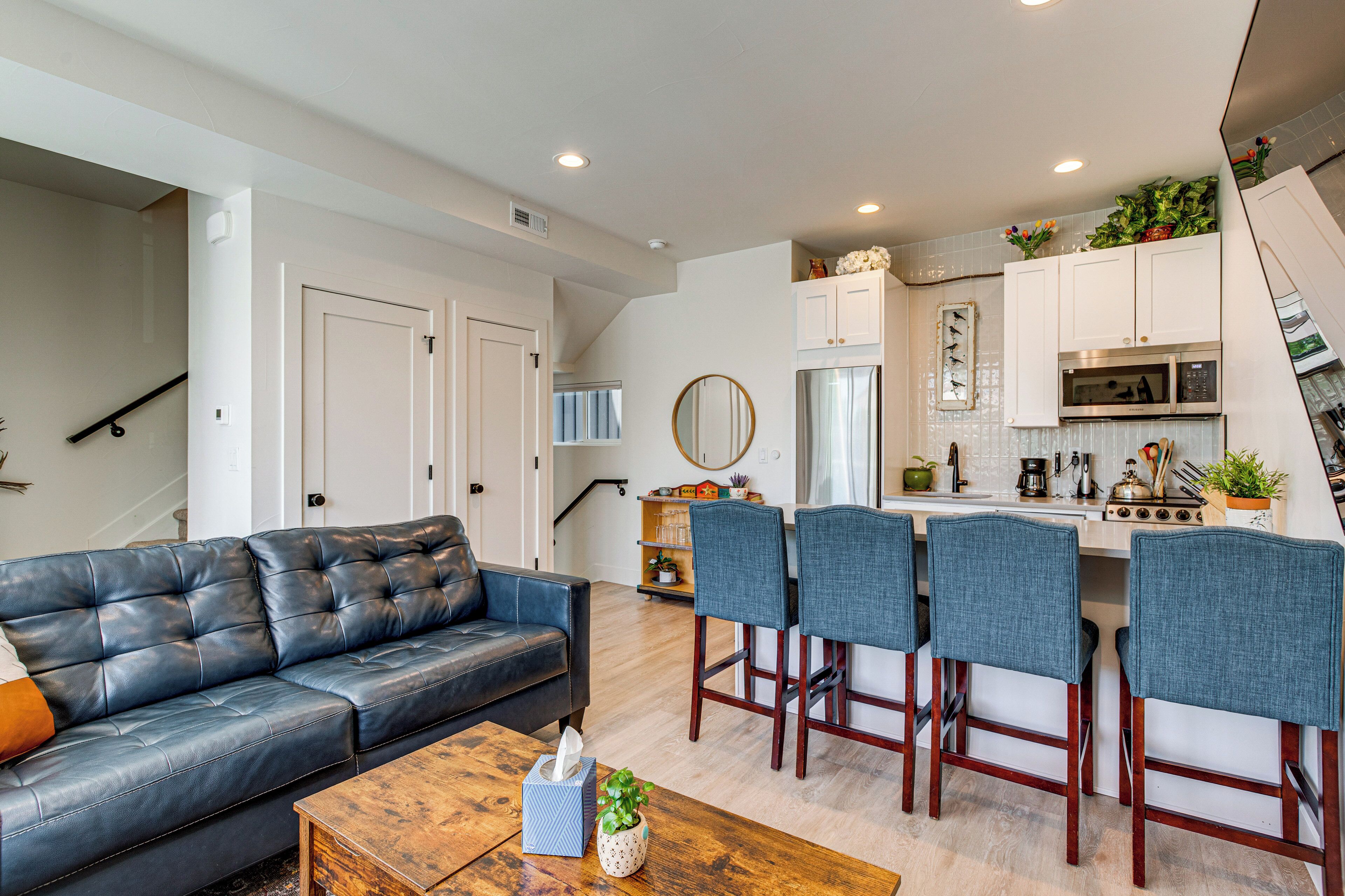 A modern kitchen with a microwave, stove, and bar stools.