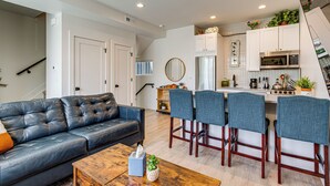 A modern kitchen with a microwave, stove, and bar stools.