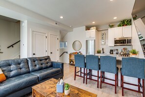 A modern kitchen with a microwave, stove, and bar stools.