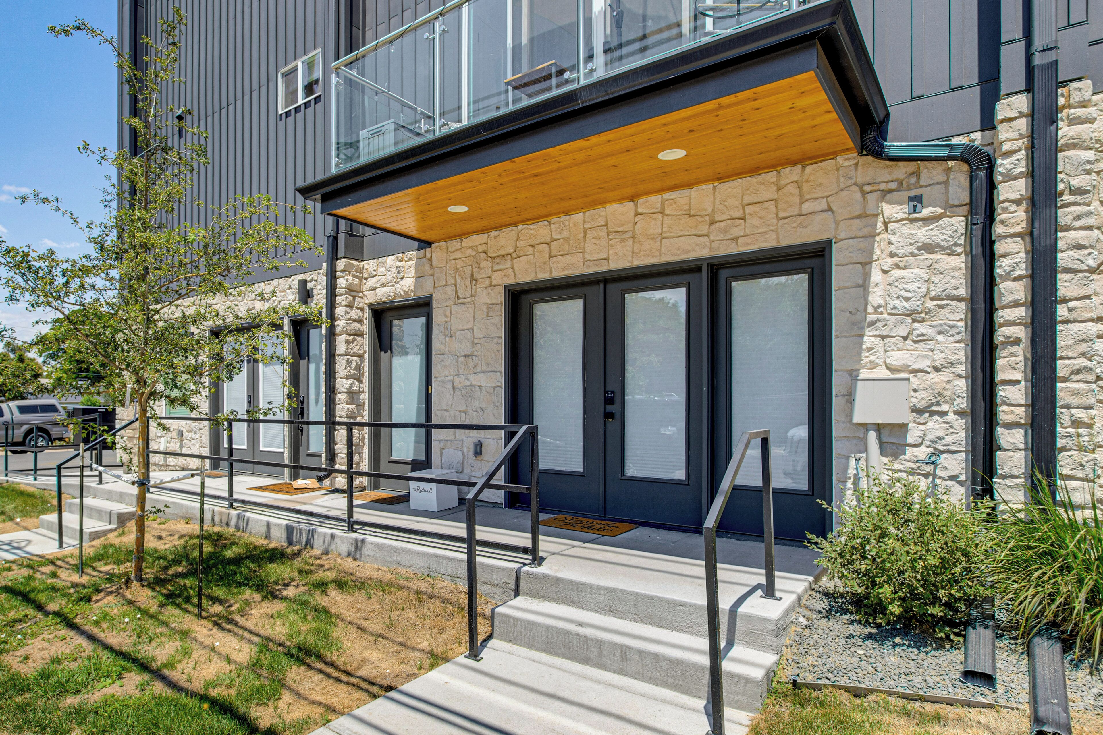 A modern building with a stone facade, large windows, and a wooden overhang.