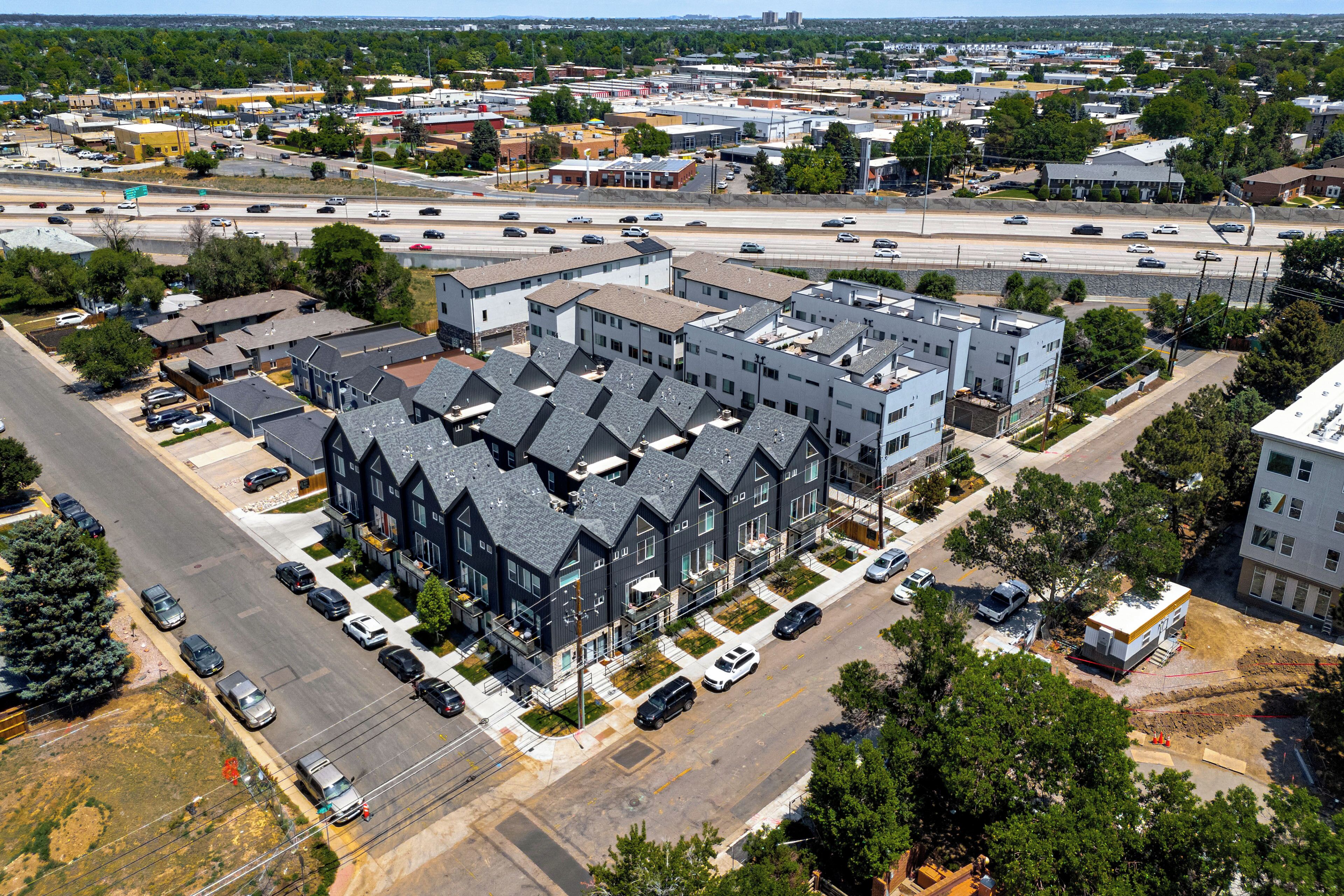 Un immeuble à plusieurs étages doté d’une architecture moderne, avec un parking et une route au premier plan.