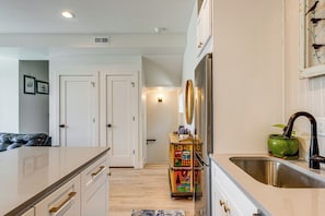 Una cocina con un lavamanos, armarios y un carrito decorativo.