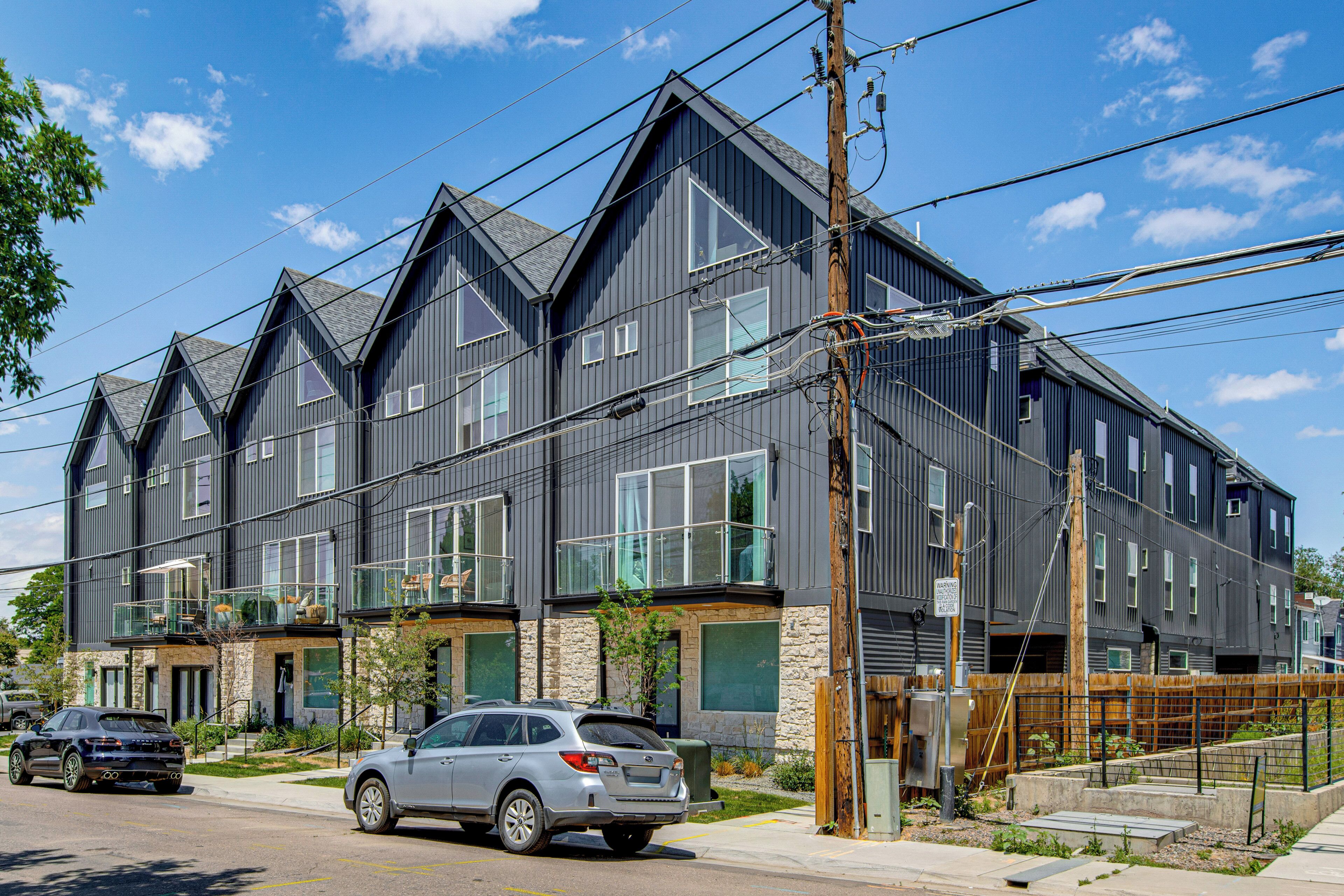 A modern multi-story building with a symmetrical facade, large windows, and a visible balcony on the second floor.