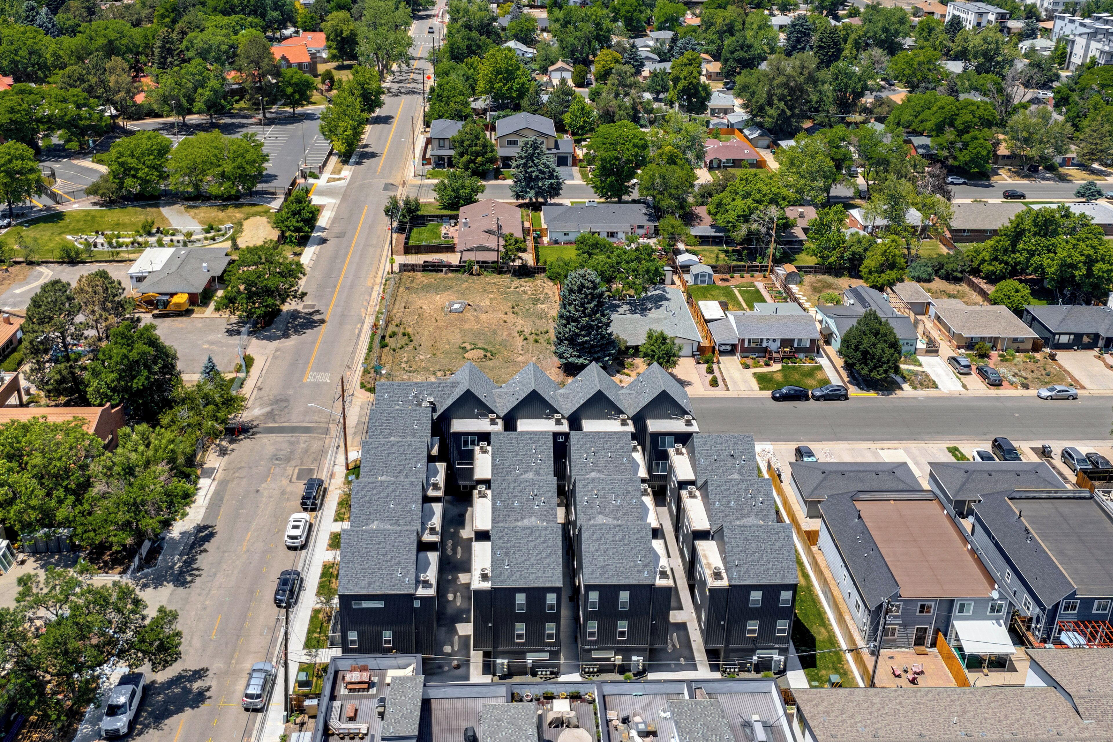 An aerial view of a residential area with multiple houses, a main road, and a parking lot.