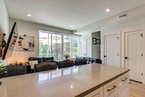 A spacious kitchen with a large island, dark leather seating, and a view of the outdoors through large windows. - Walkable Location: Pet-friendly Denver Townhome (Denver)