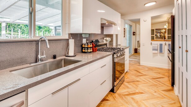 A modern kitchen with a large island, stainless steel appliances, and a view to the outdoors. - Stylish MCM Retreat: 27 Days or More (Palm Desert)