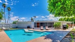 A modern house with a swimming pool, outdoor seating, and a large tree. - Stylish MCM Retreat: 27 Days or More (Palm Desert)