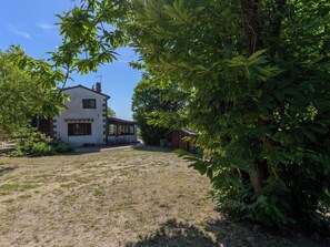 Ein zweigeschossiges Haus mit überdachter Terrasse und Garten.