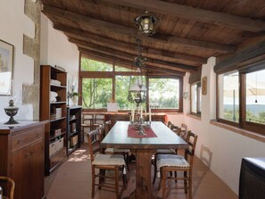 Ein rustikaler Essbereich mit Holzmöbeln, einem großen Tisch und Blick auf Grünflächen.