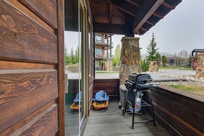 Ein Holzfassade mit einem Steinkamin, einem Grill und Blick auf ein mehrstöckiges Gebäude mit Balkonen.