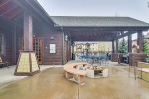Un espacio al aire libre techado con un banco de hormigón, una chimenea y una mesa con sillas.