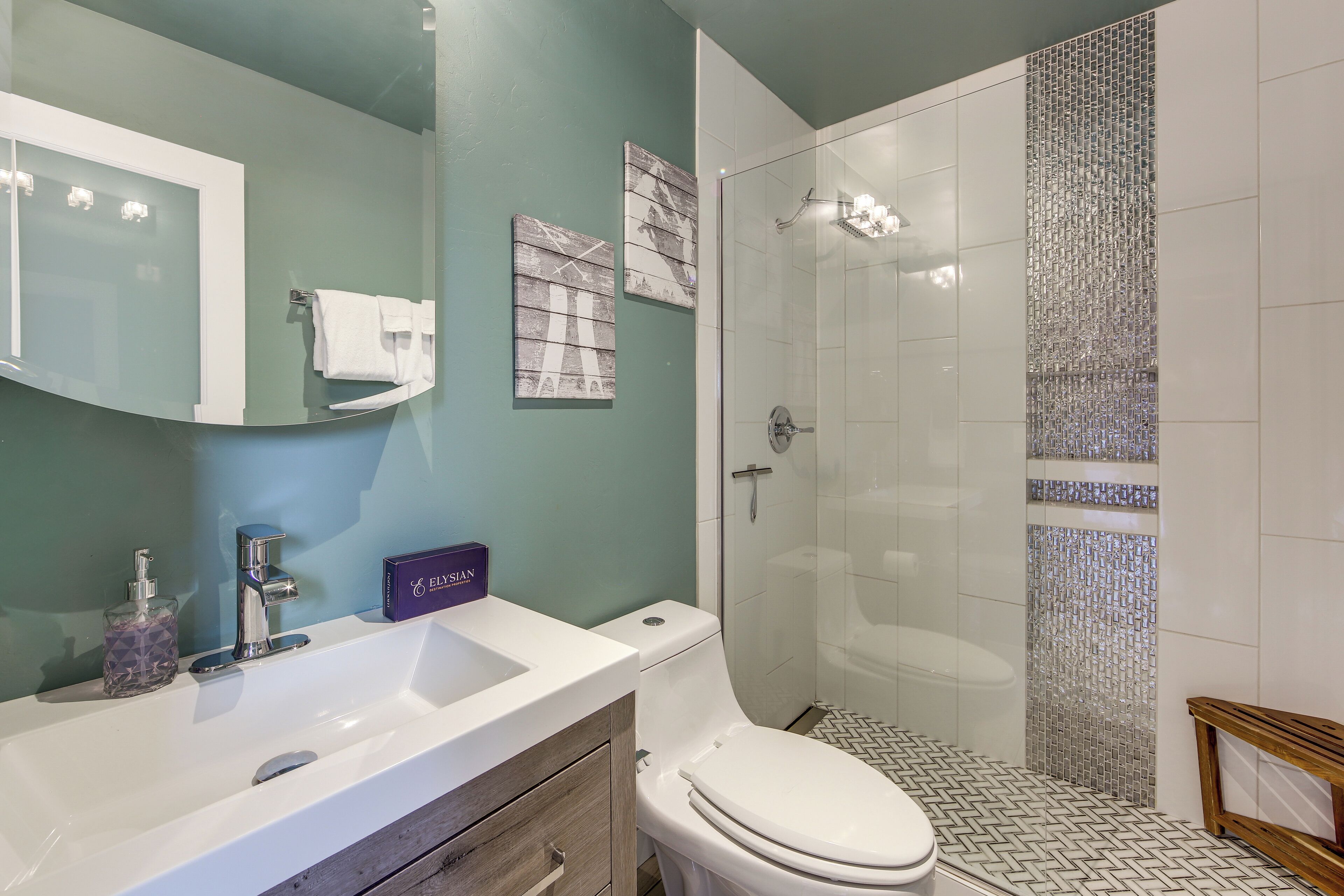 A bathroom with a white sink, a toilet, a glass shower enclosure, and a mirror.
