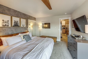 Ein Schlafzimmer mit Bett, Kommode, Fernseher und gerahmten Bildern an der Wand.