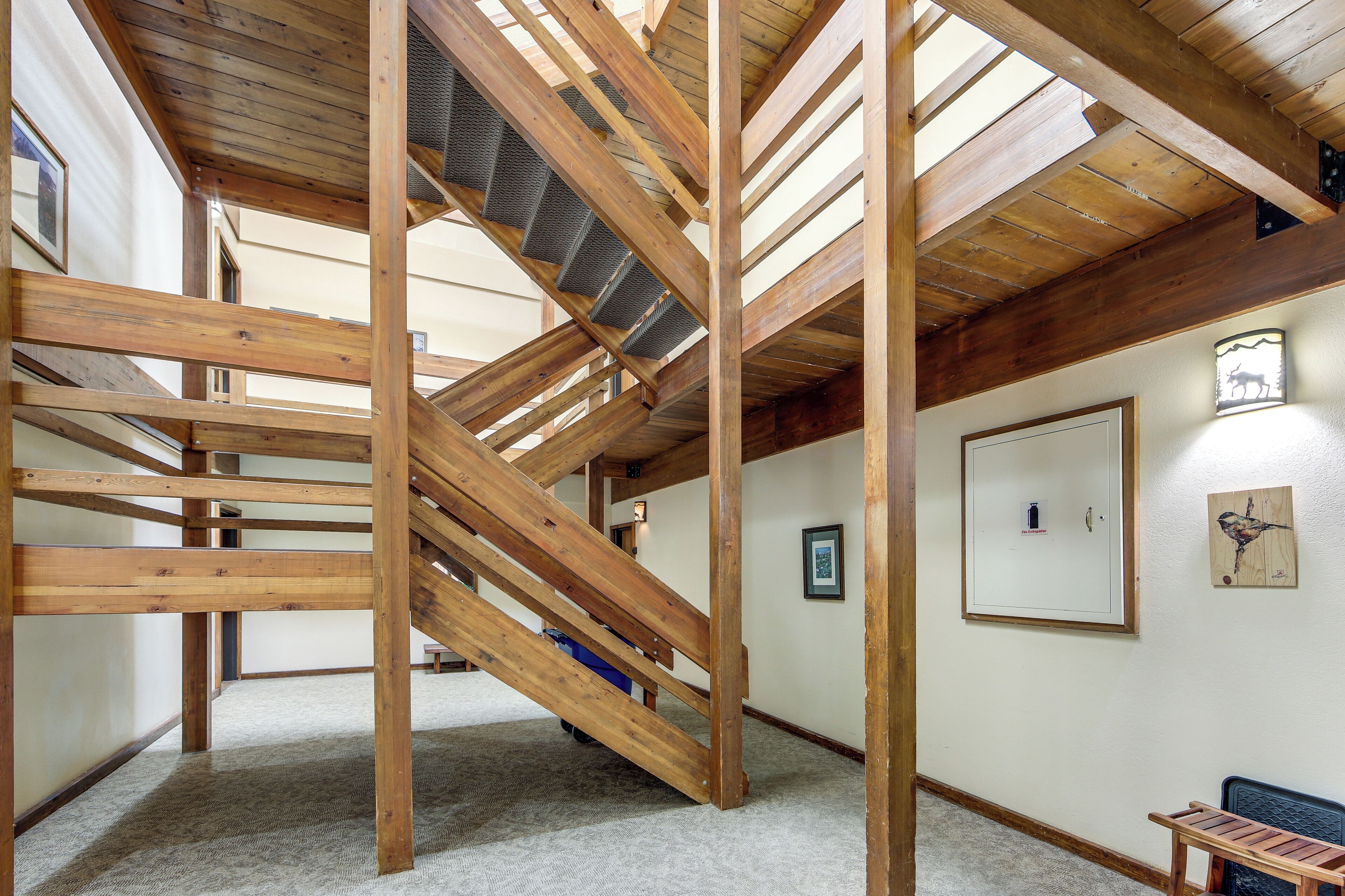 A room with exposed wooden beams, a staircase, and a framed picture on the wall.