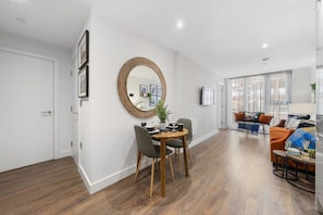A modern apartment with a dining area, a living room, and a large window. - Luxury Liverpool Waterfront Apartment (Merseyside)