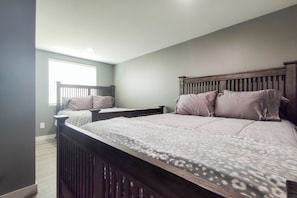 A bedroom with a large bed, a smaller bed, and a window. - Whale Watch, Fish & Hike Glaciers! Homer Apartment (Homer)