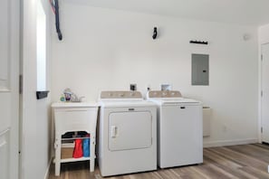 A laundry room with two washing machines, a dryer, and a utility sink.