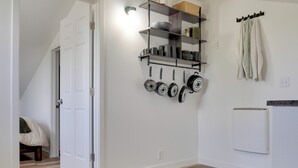 Una cocina con puerta blanca, suelo de madera, un colgador de ollas en la pared y un radiador blanco.