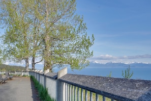 A pathway with benches, a railing, and a view of a lake with mountains in the distance. - Fish Kachemak Bay! Adventure Base Near Homer Spit (Homer)