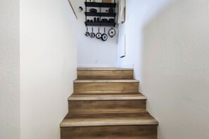 A wooden staircase leading to a kitchen area with pots and pans hanging on the wall.