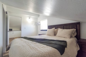 A bedroom with a bed, a wooden headboard, a bedside table, and a window. - Fish Kachemak Bay! Adventure Base Near Homer Spit (Homer)