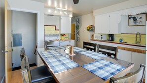 Eine Küche mit Esstisch, Stühlen, Deckenventilator und Schränken.