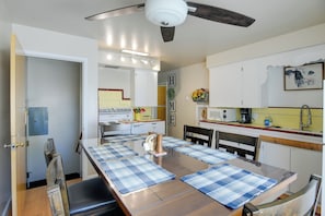 A kitchen with a dining table, chairs, a ceiling fan, and cabinets.