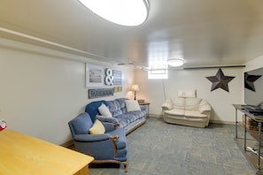 A living room with a blue sofa, a beige armchair, a wooden table, and a TV stand.