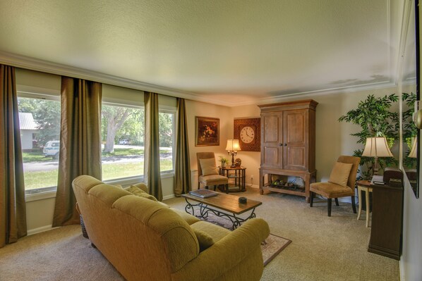 A living room with a sofa, armchairs, a coffee table, a lamp, a clock, and a cabinet.