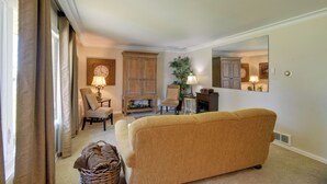 Ein Wohnzimmer mit einer Couch, Sesseln, einer Lampe, einem Schrank und einem Spiegel.