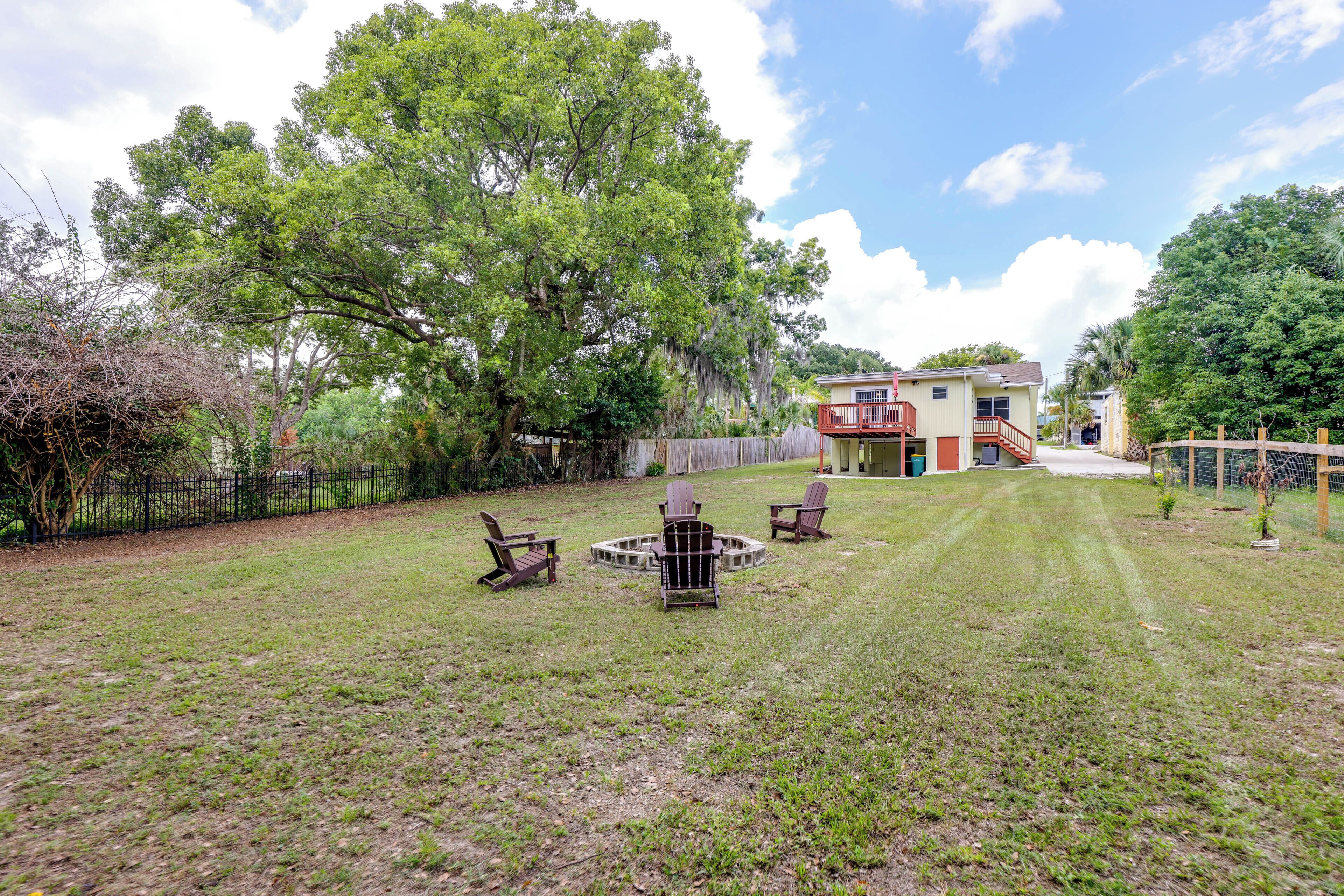 A backyard with a fire pit, chairs, and a house in the background.