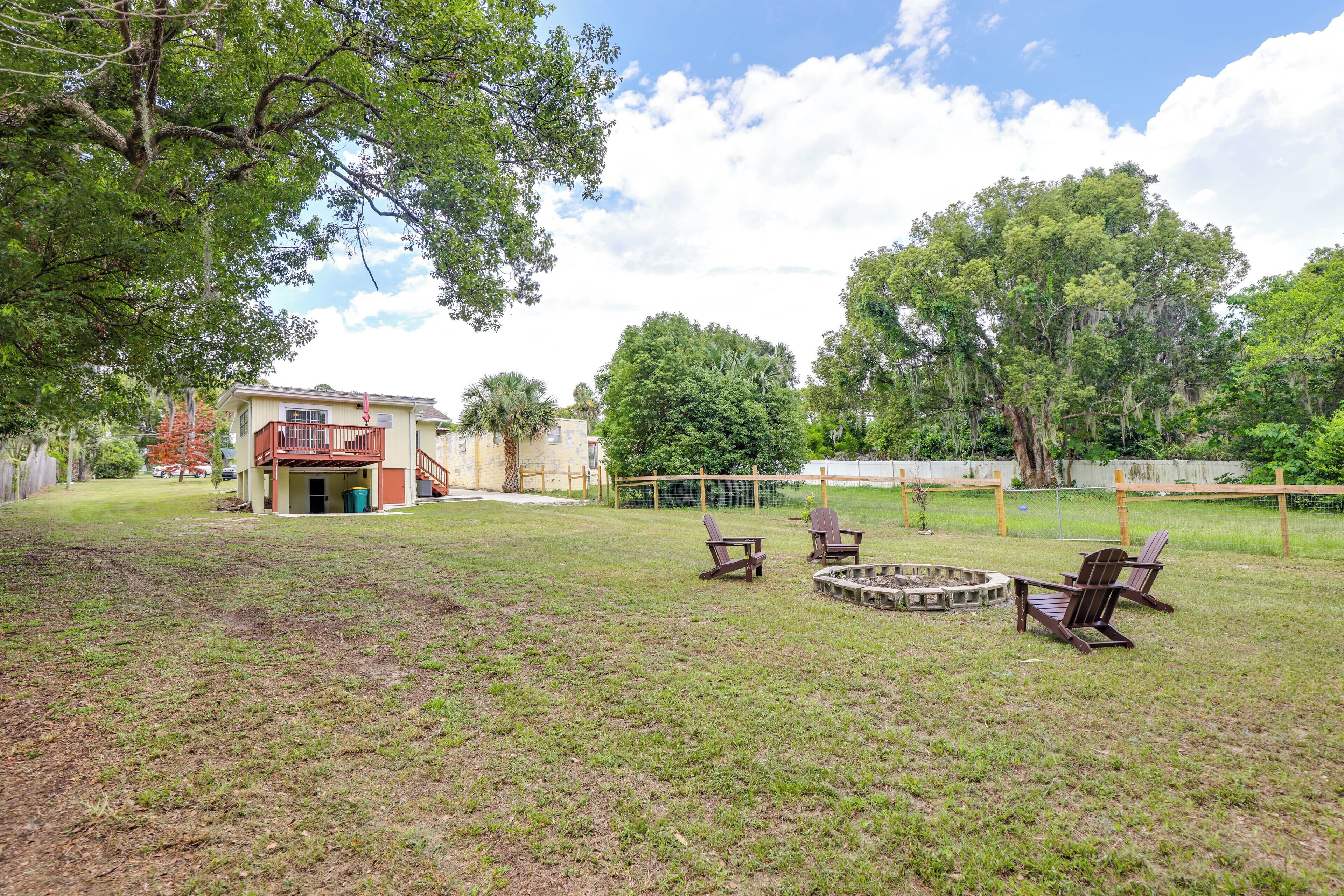 A backyard with a fire pit, outdoor seating, and a house with a balcony.