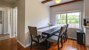 A dining area with a wooden table, chairs, a window with a view, and a ceiling light fixture.