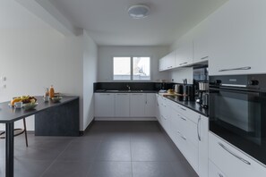 A modern kitchen with white cabinets, a black countertop, and a window above the sink. - House in Landunvez Near Penfoul Beach (Landunvez)