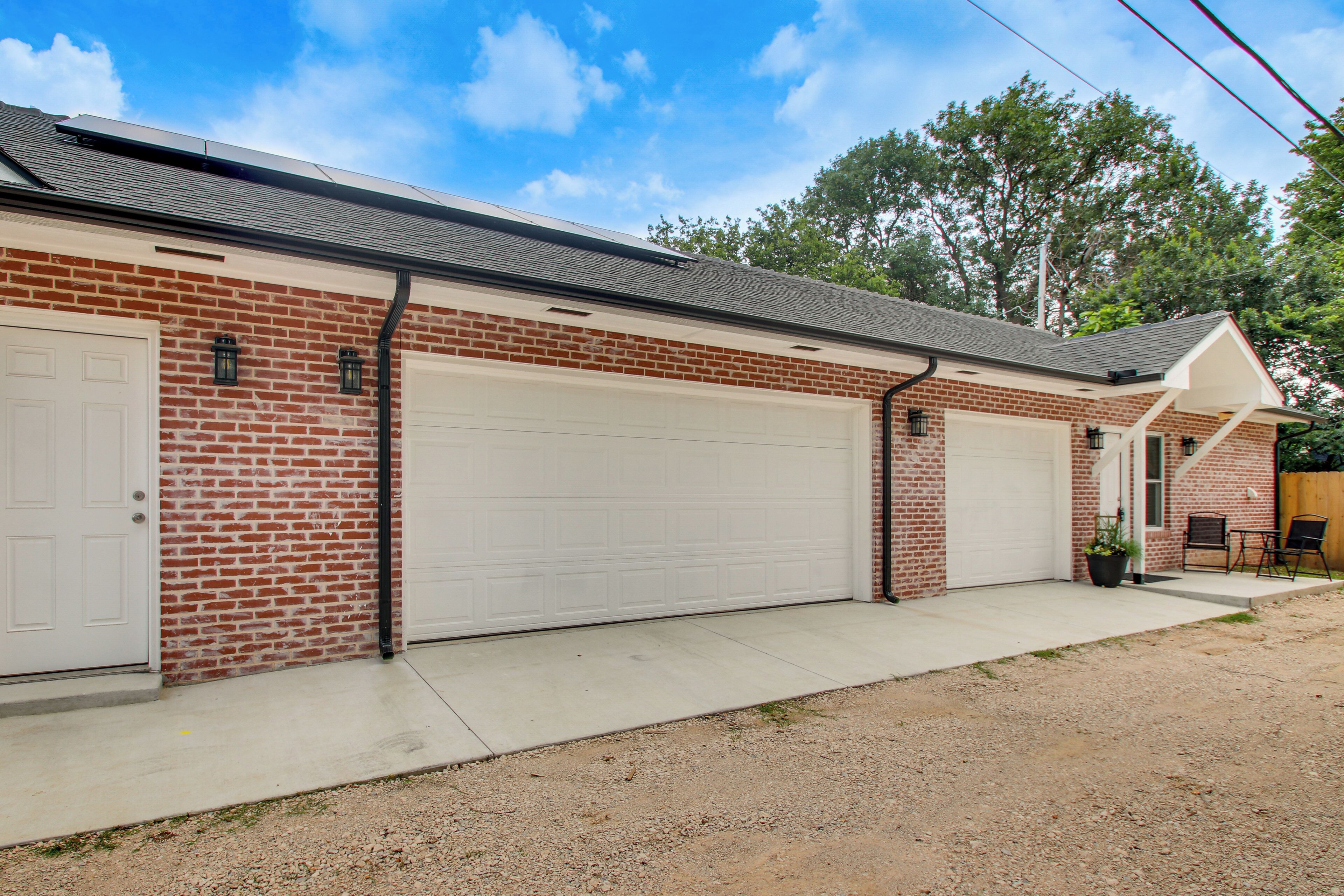 A two-story brick building with a garage and a covered porch.