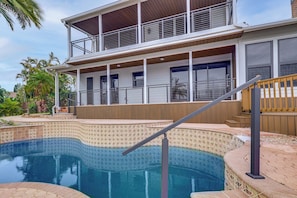 Ein zweistöckiges Haus mit Schwimmbad, Balkon und einer Holzterrasse.