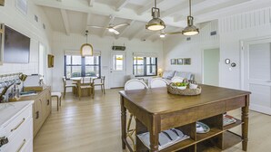 A spacious kitchen with wooden cabinets, a dining table, and a ceiling fan. - Casa Del Mare Beach to Bay on Alligator Point (Panacea)