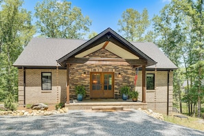A two-story house with a stone facade, a wooden front door, and a small porch with potted plants. - Roxboro Lake Family Retreat and Spa (Prospect Hill)