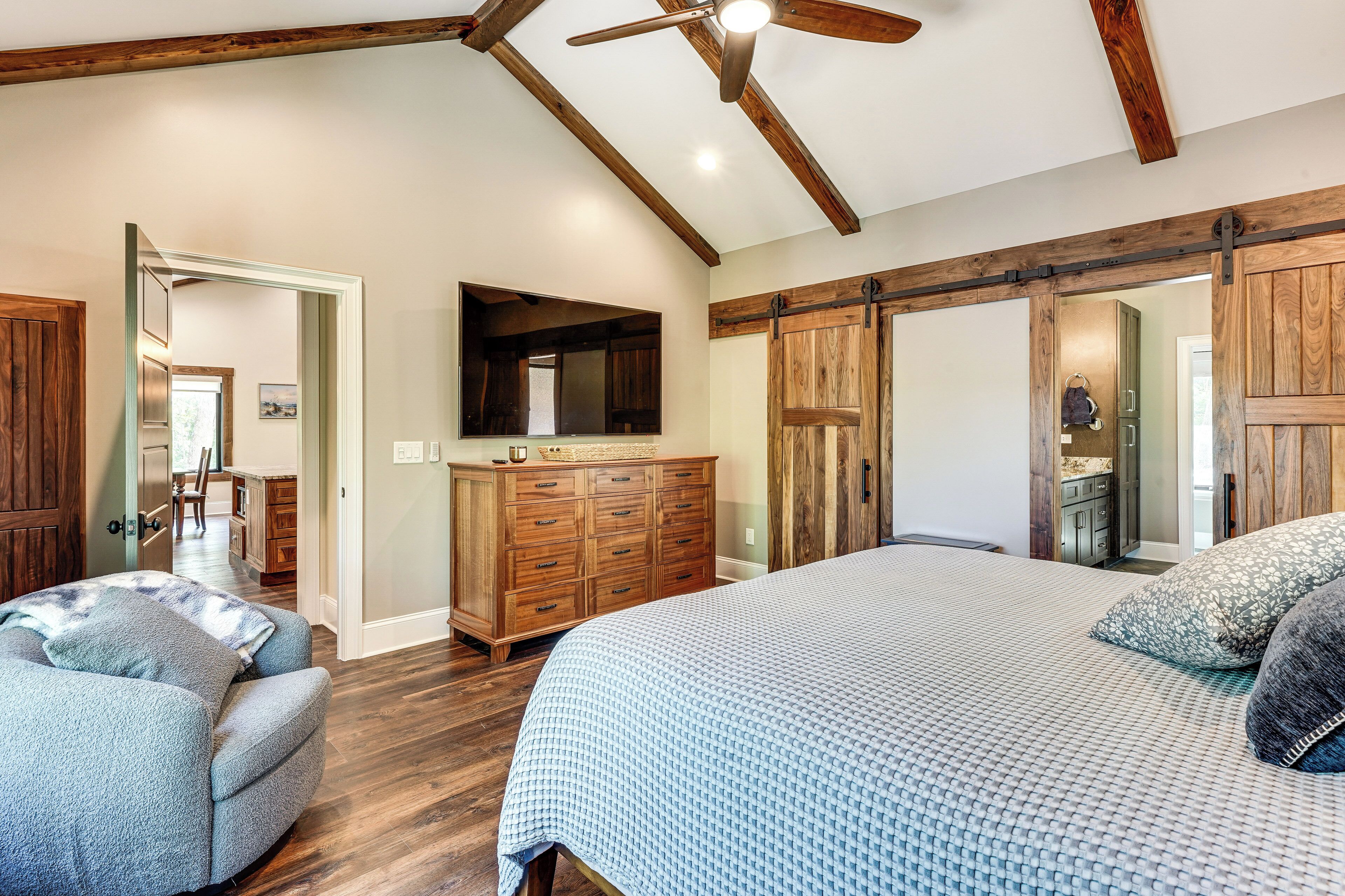 A bedroom with a bed, a dresser, a mirror, and a ceiling fan.