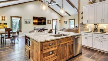 A spacious kitchen with a large island, wooden cabinets, and a farmhouse ceiling.