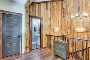 A wooden interior with a dark door, a staircase with a metal railing, and a wall-mounted light fixture. - Roxboro Lake Family Retreat and Spa (Prospect Hill)