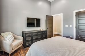 A bedroom with a bed, a dresser, a chair, and a television on the wall. - Roxboro Lake Family Retreat and Spa (Prospect Hill)