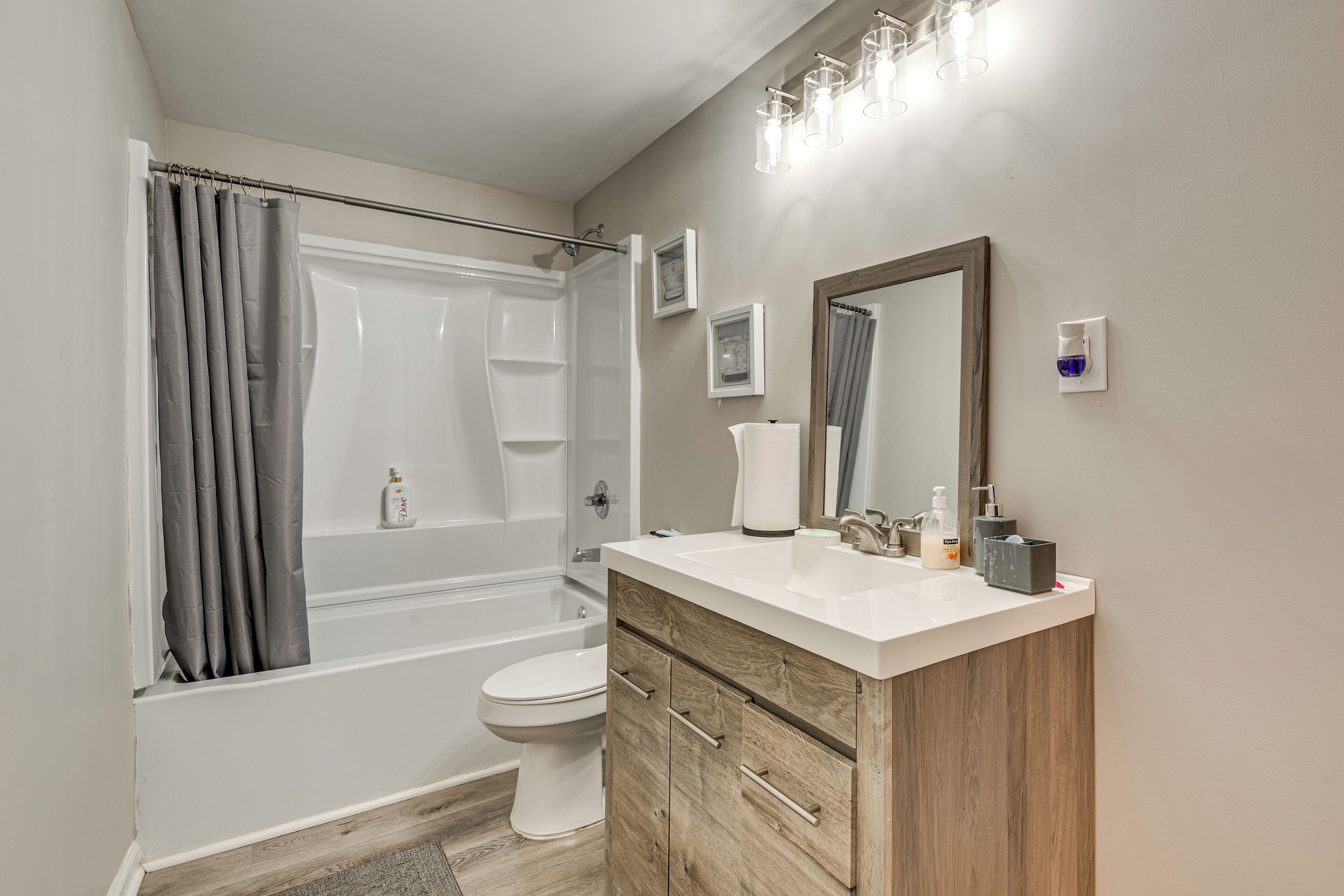 A modern bathroom with a bathtub, toilet, vanity with a mirror, and a shower curtain.