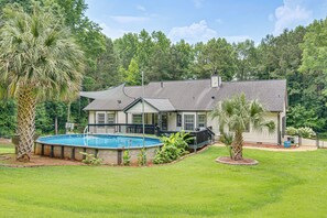 A two-story house with a swimming pool, surrounded by a well-maintained lawn and trees. - Pool, Hot Tub & Game Room! Stockbridge Oasis (Stockbridge)